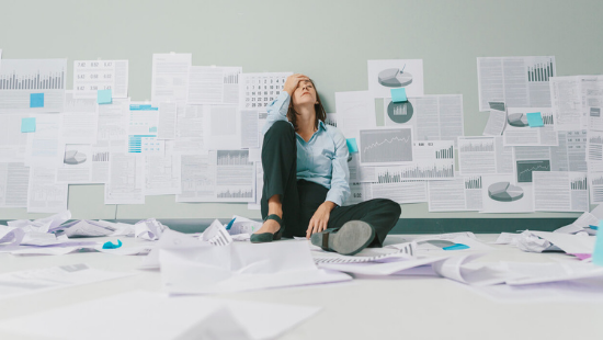 Frustrated woman sitting in a pile of banking papers - Why we developed KlariVis